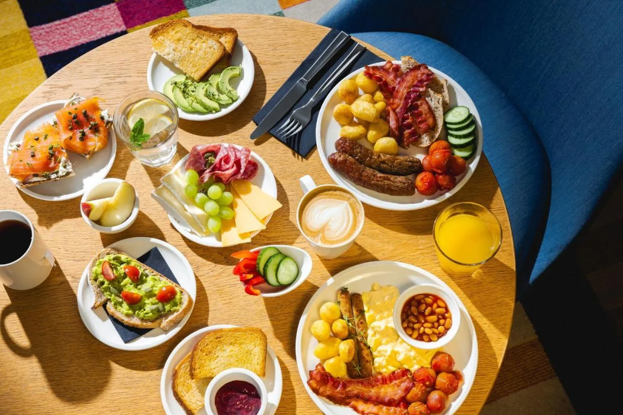 a wooden table with plates of food on it at citizenM London Victoria Station in London