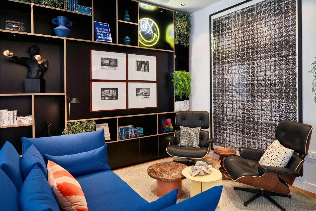 a living room with a blue couch and two chairs at citizenM London Victoria Station in London