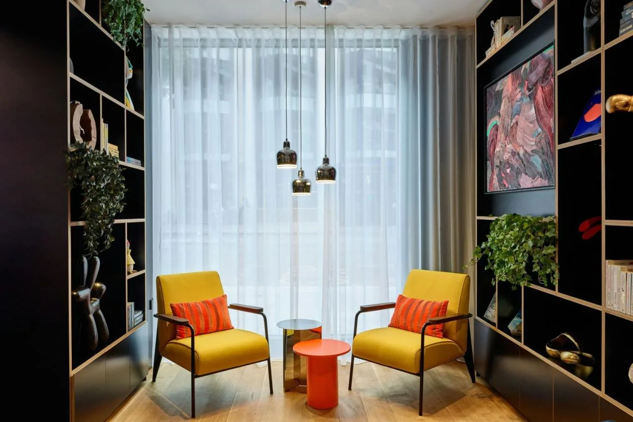 two chairs and a table in a room with a window at citizenM London Victoria Station in London