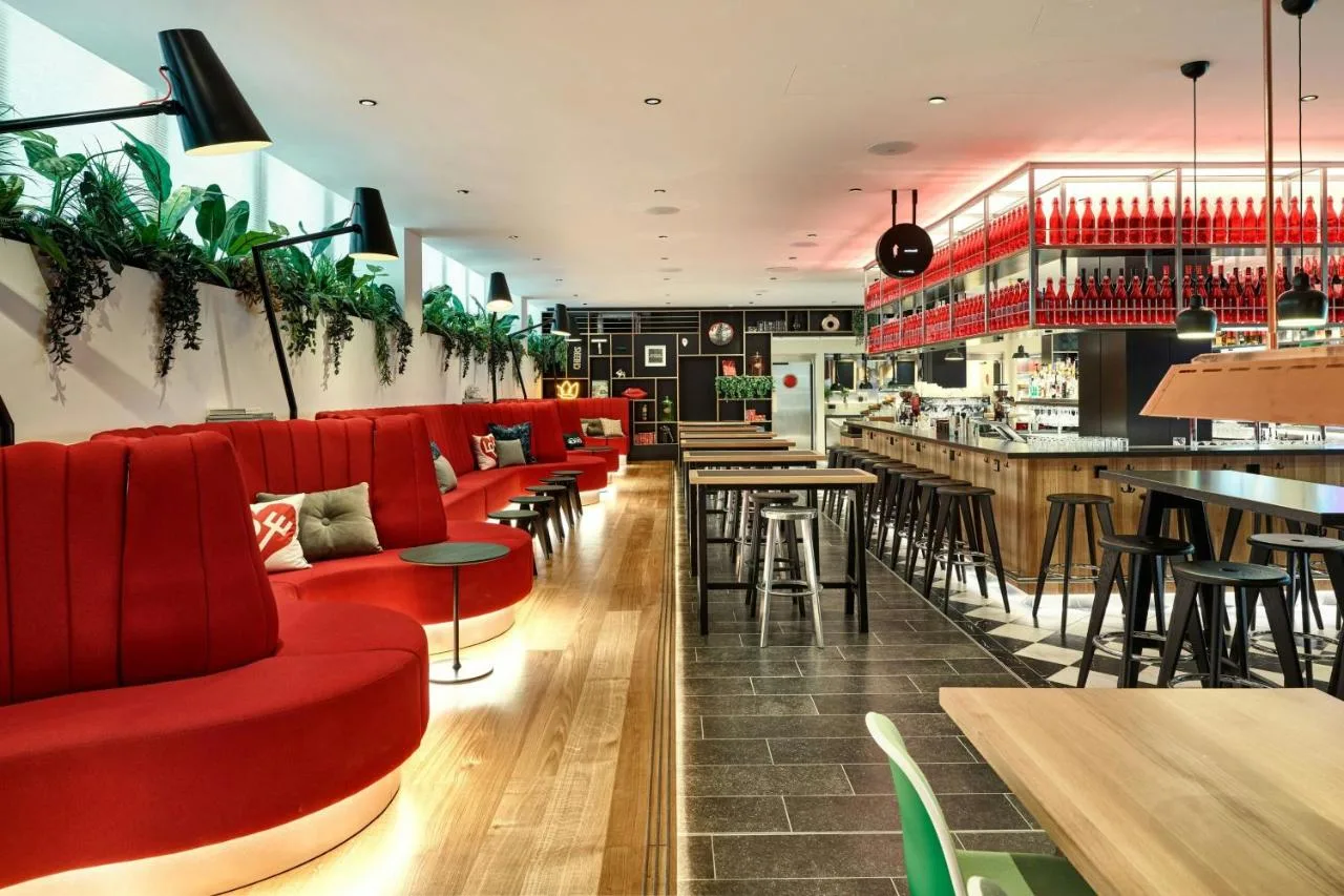 a restaurant with red chairs and a bar at citizenM London Victoria Station in London